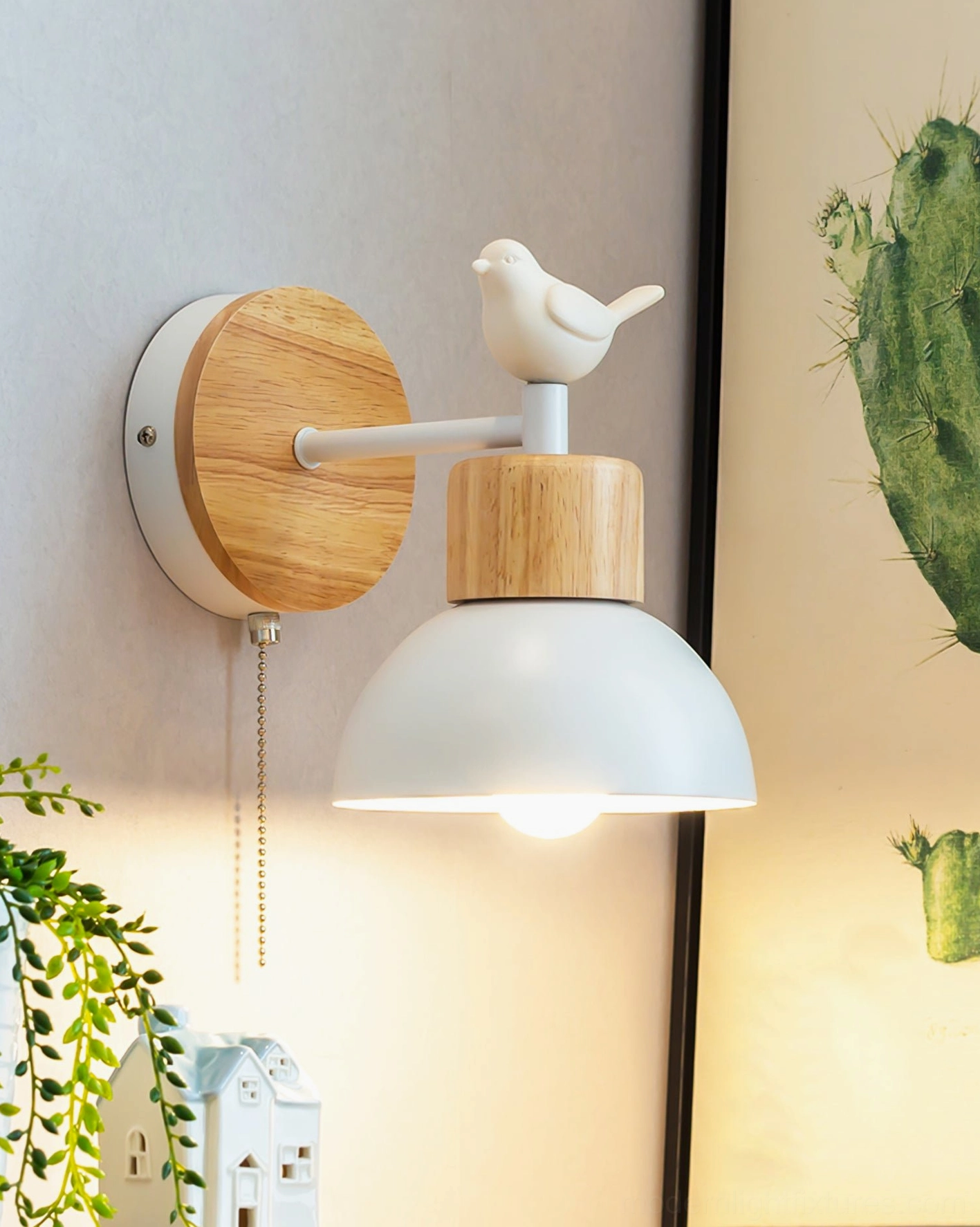 Bird wall sconce with pull chain switch mounted on wall with cactus decor and green plants