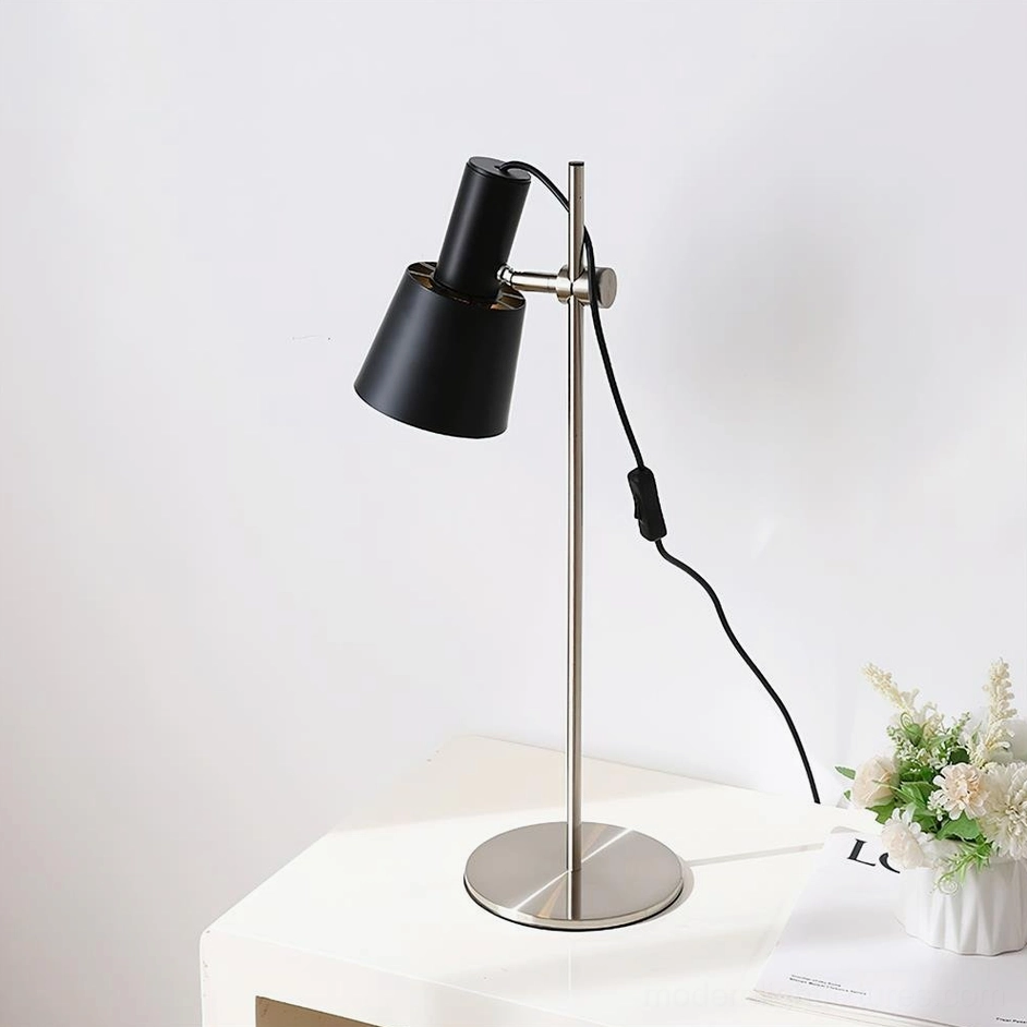 Modern matte black adjustable table lamp with silver metal base on white side table with flowers