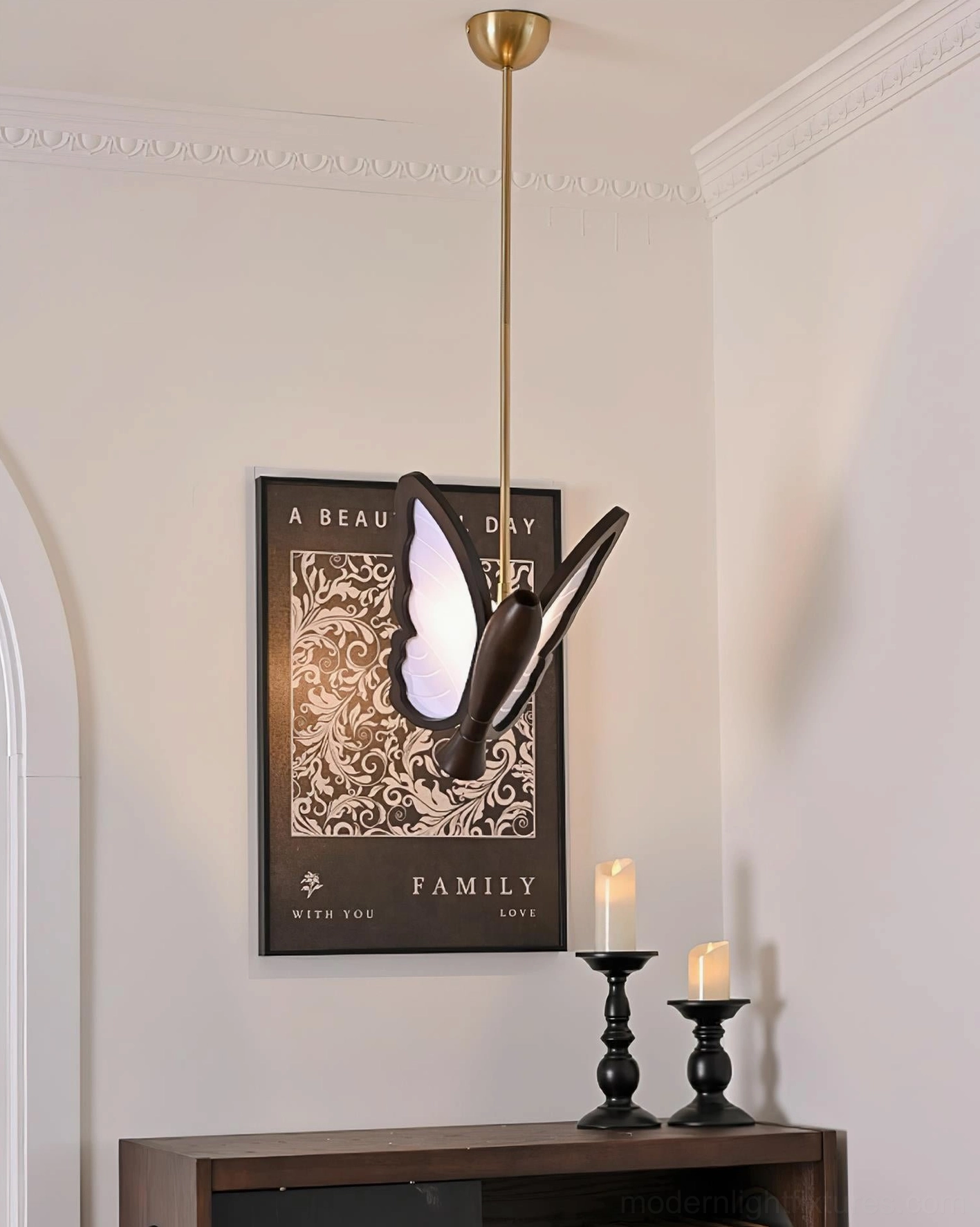 Black butterfly pendant light installed in entryway above wooden console table with sculptural side profile visible