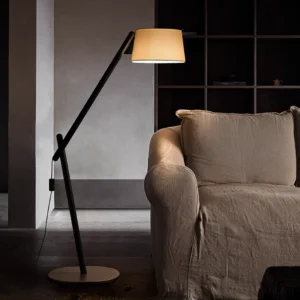 Black arc floor lamp three-quarter view in contemporary living room with dark sofa and warm lighting
