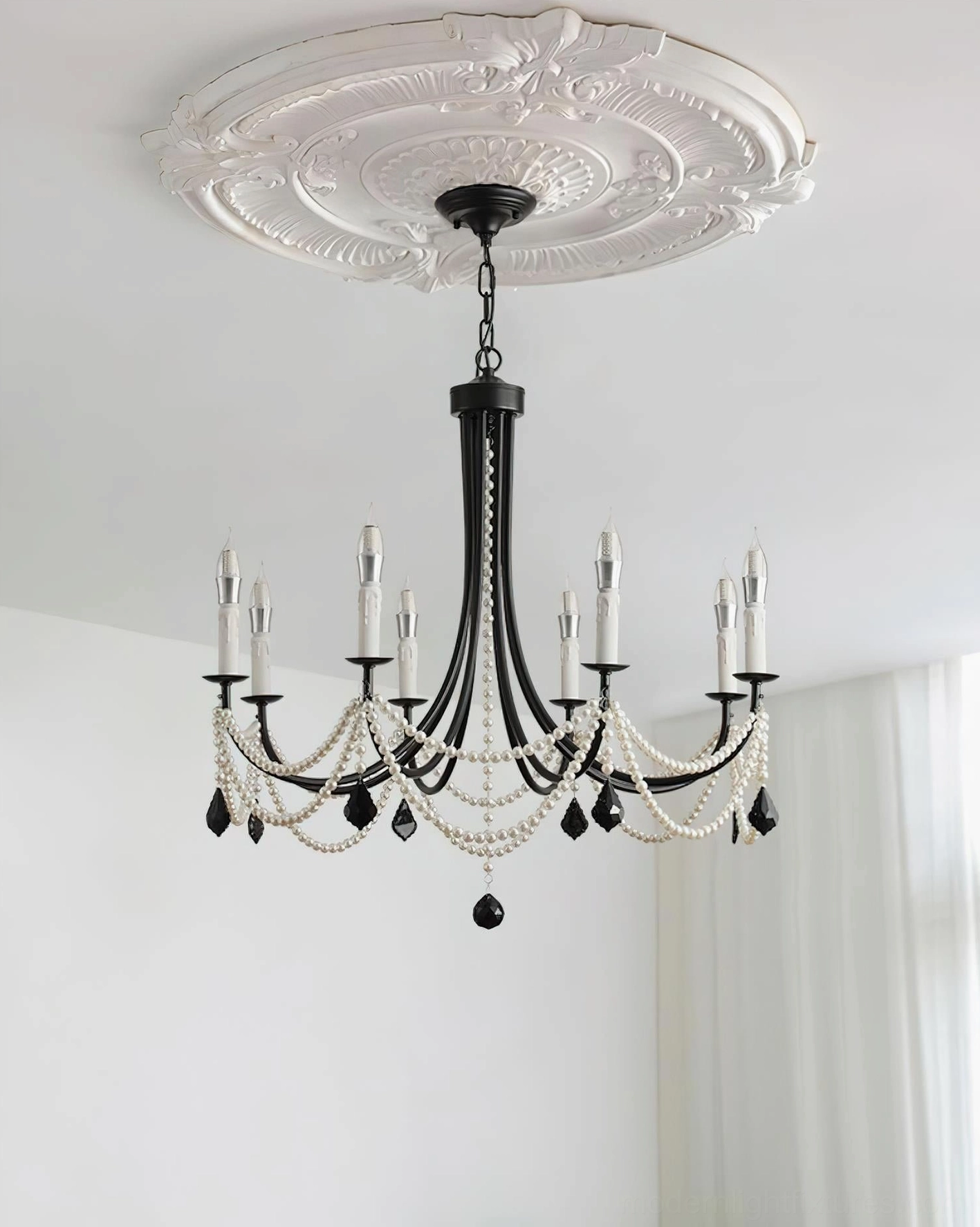 Black crystal pendant chandelier mounted on ornate white ceiling medallion in minimalist living space