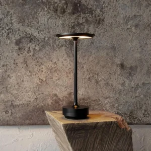 Black cordless LED table lamp with sleek metal body displayed on industrial wooden block