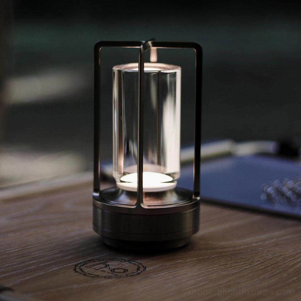 Black cordless table lamp on office wooden desktop with matte black base and transparent glass enclosure, front view
