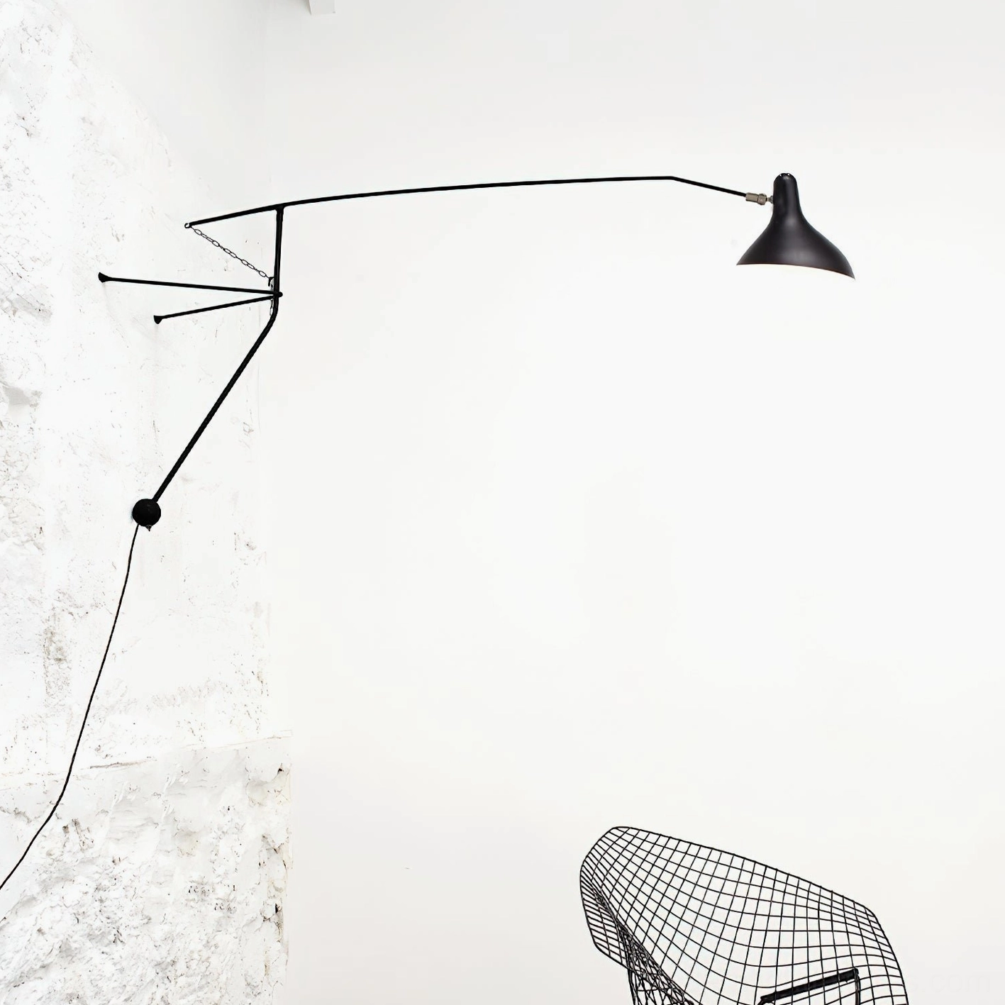 Black wall-mounted articulating lamp side profile exposed power cord