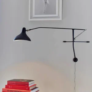 Black swing arm wall lamp with stabilizing chain mounted on interior wall