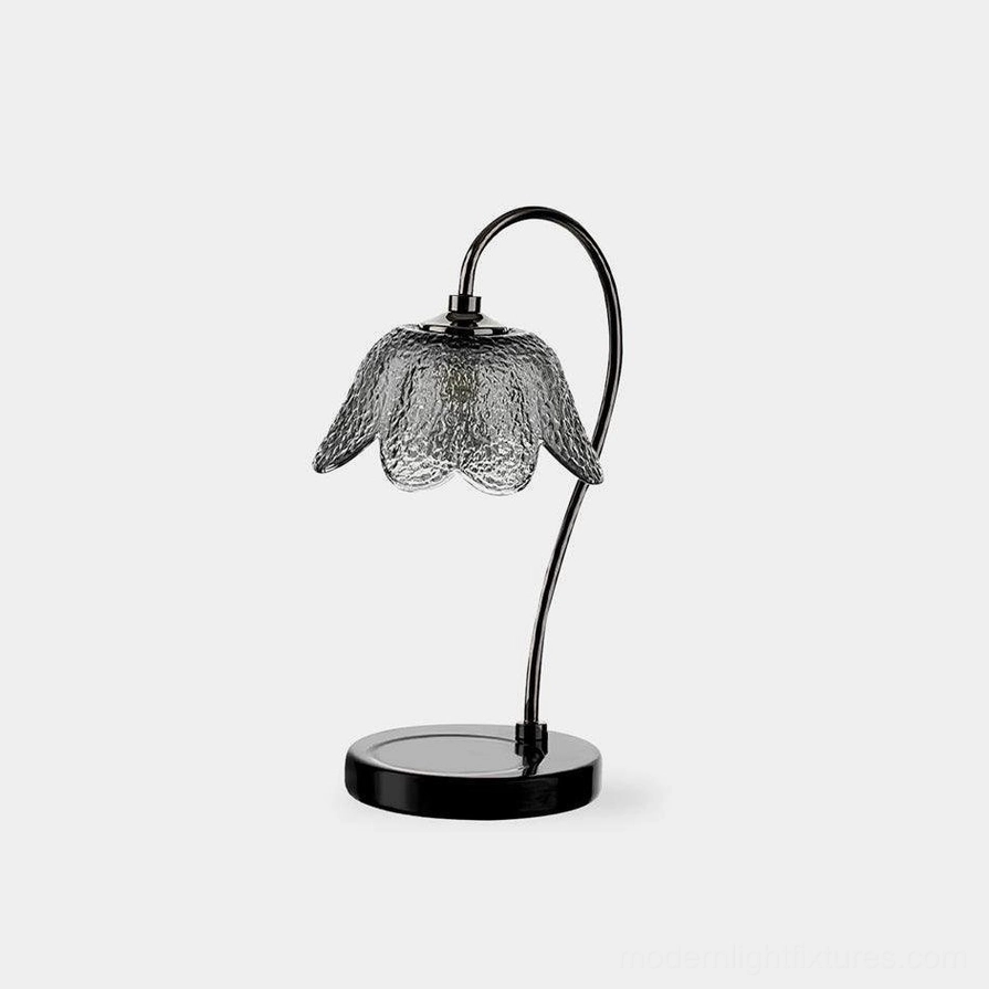 Black marble candle warmer lamp with textured flower glass shade and curved metal arm on white background