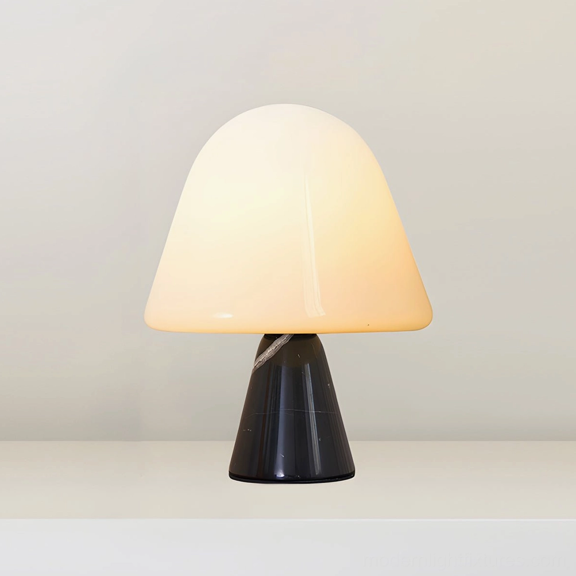 Black marble base mushroom table lamp with white opal glass shade on dark wood furniture in sophisticated interior design setting