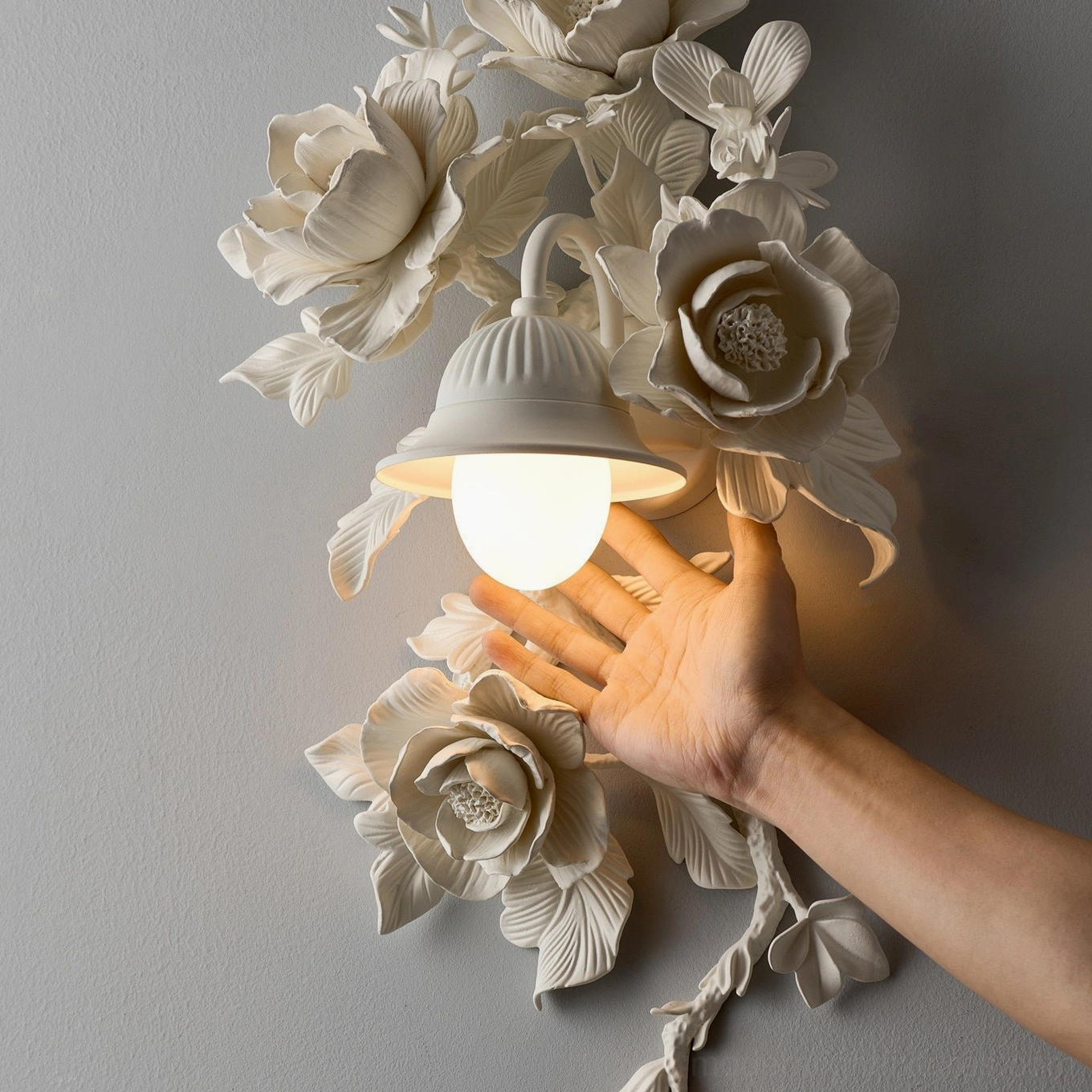 Black matte Elysia Bloom rose sconce mounted on light wall, dramatic sculptural botanical relief with warm downlight