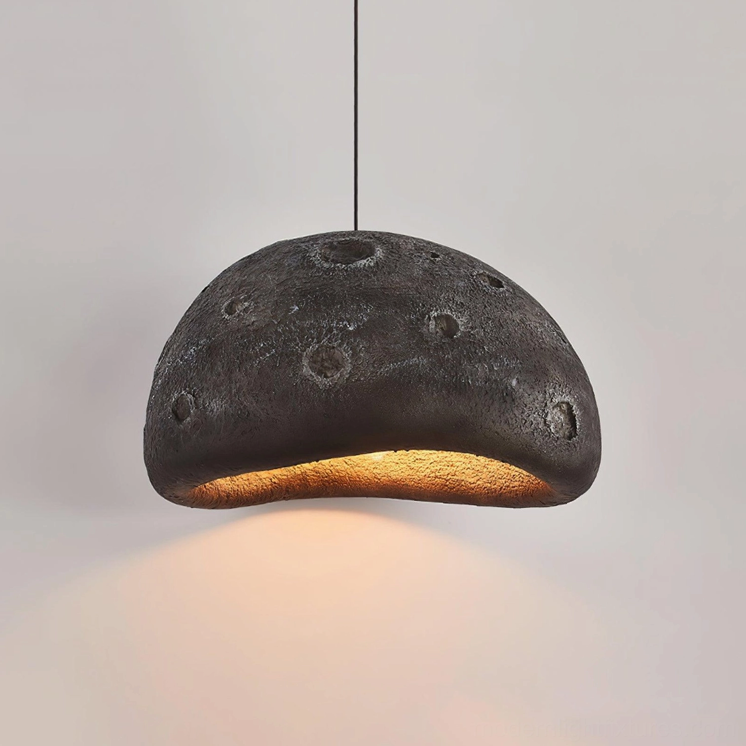 Black meteorite crater pendant light in monochromatic modern space with dramatic lighting effect