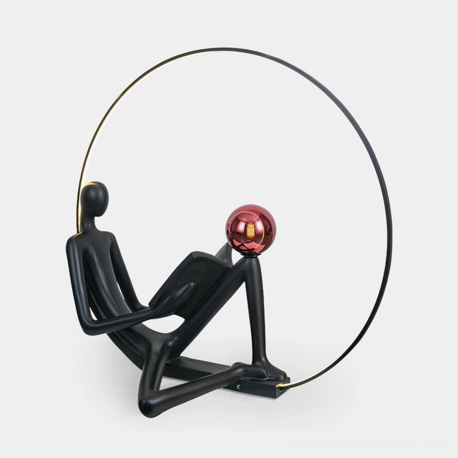 Black reading statue floor lamp with red accent globe, front studio view on white background, modern art lighting sculpture