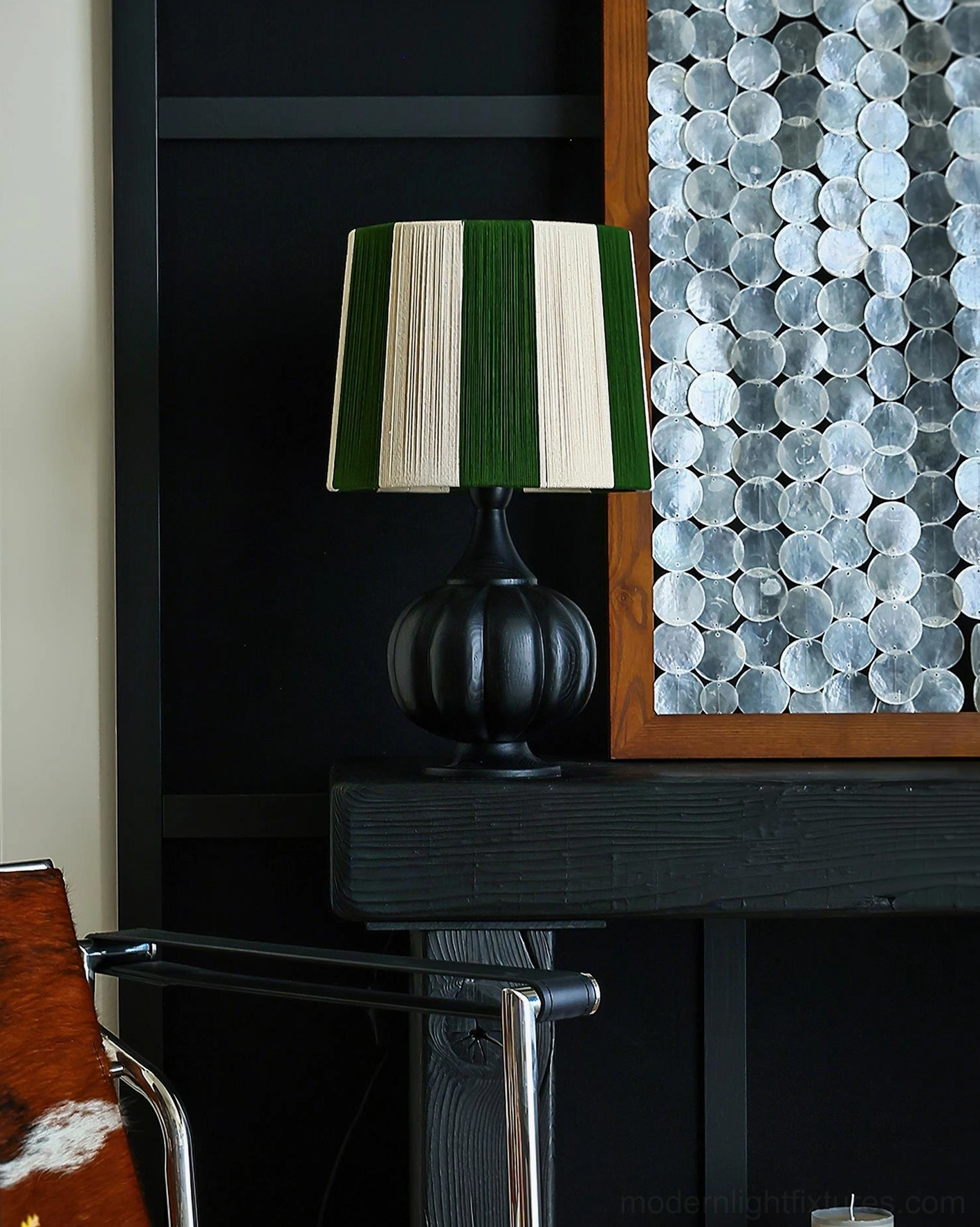 Black pumpkin base striped table lamp on dark vintage wooden cabinet in moody interior setting