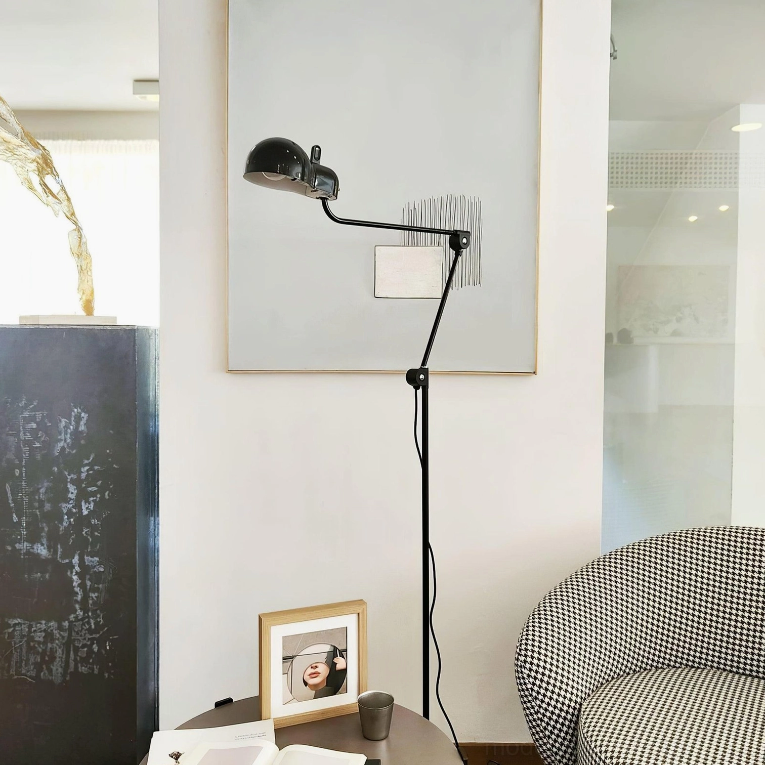 Black articulated swing arm lamp positioned in corner of modern minimalist living room with wall art accent