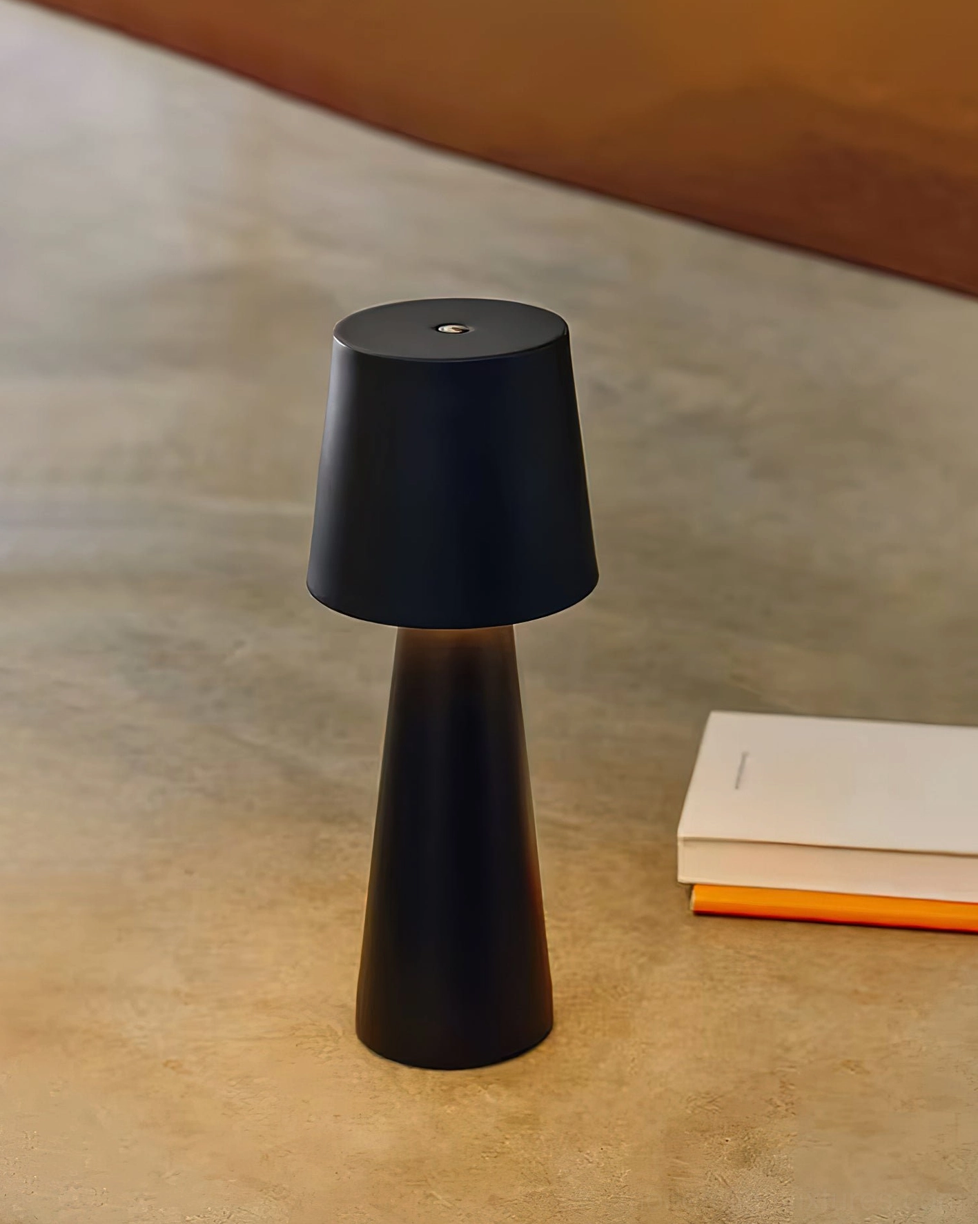 Matte black tapered ceramic table lamp on stone desktop with stacked books minimal