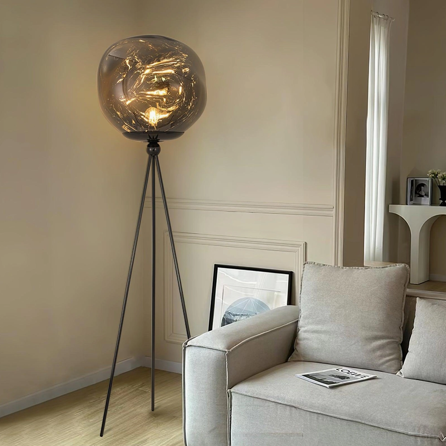 Minimalist tripod floor lamp with matte black stand and smoked brown glass shade in living room lounge setting