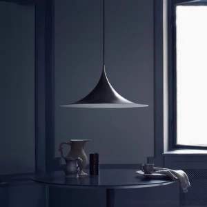 Black trumpet pendant fixture hanging in contemporary dining nook with warm ambient lighting