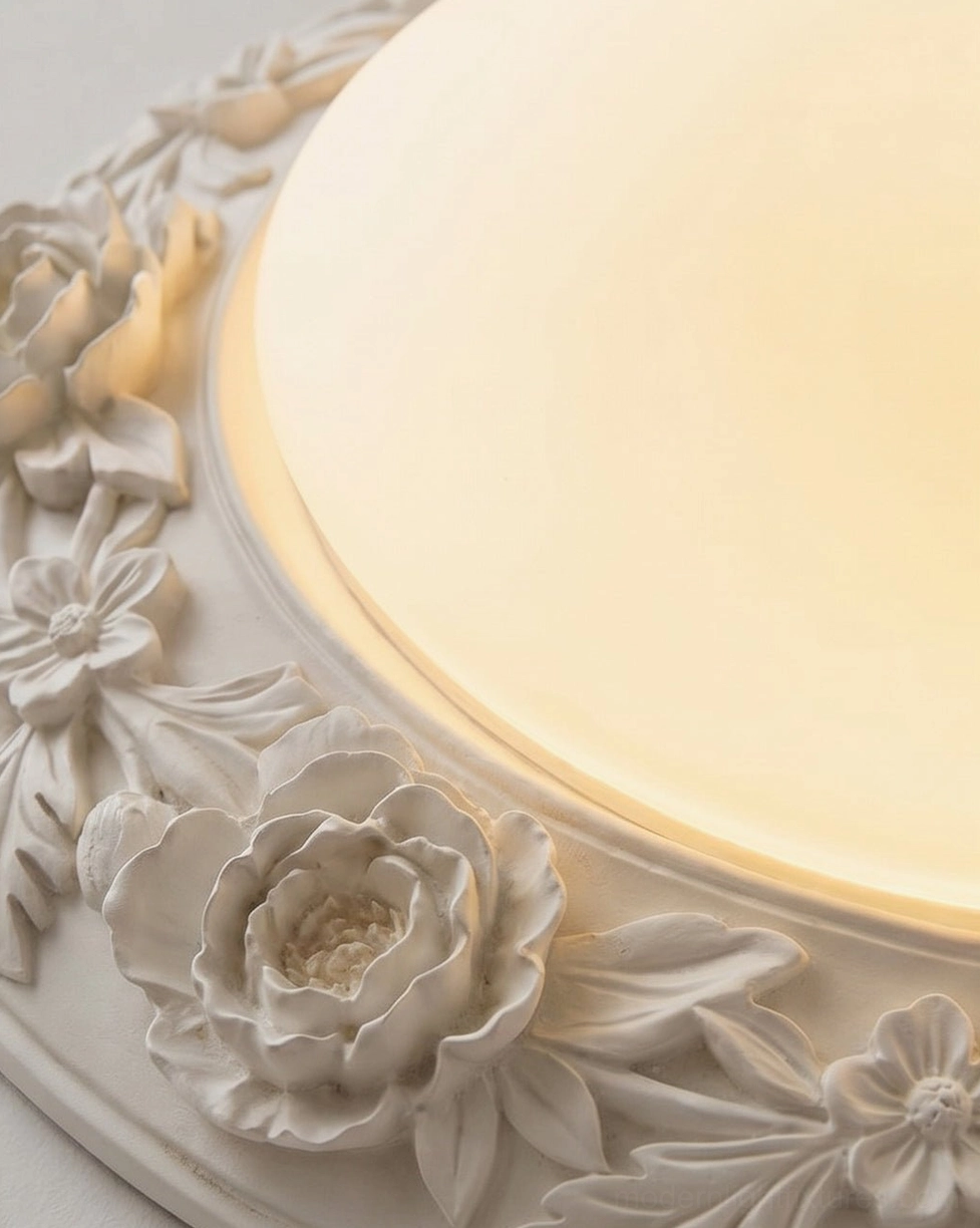 Close-up detail of Blancora ceiling light showing hand-carved rose and leaf relief trim, frosted glass dome, and warm glowing LED