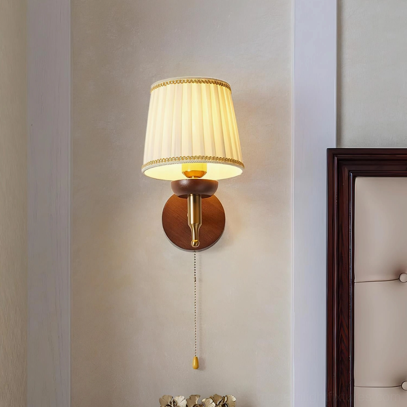 Blixen wall sconce in home corridor with walnut and brass construction and gold pull cord