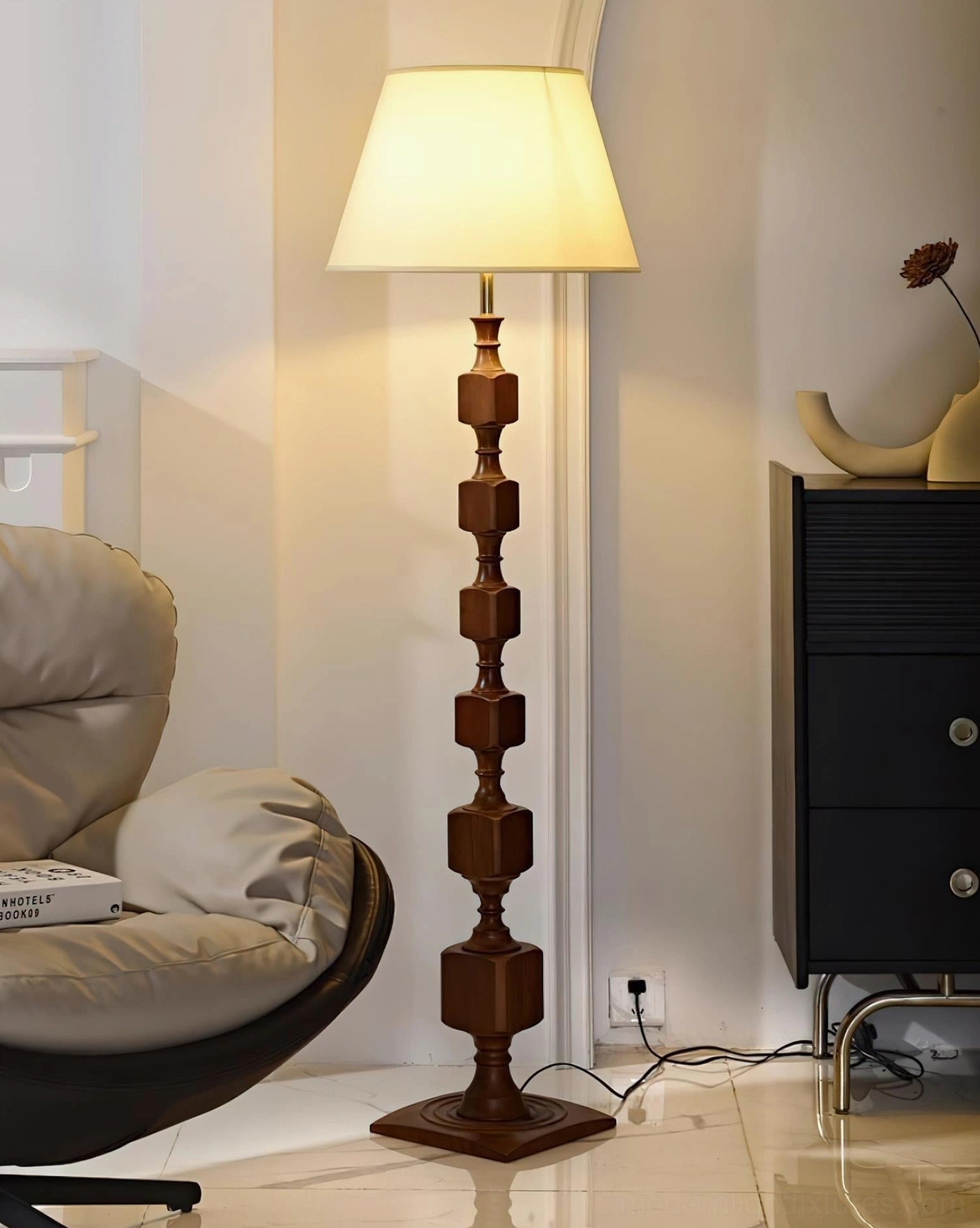 Walnut-colored Blockora stacked floor lamp with fabric shade in modern living room beside lounge chair, showing warm wood tone and ambient lighting