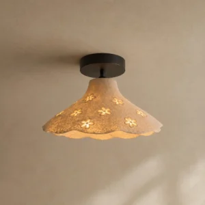 Bloomira flush mount ceiling fixture with warm glowing light passing through flower apertures, three-quarter angle on neutral wall showing scalloped rim design detail
