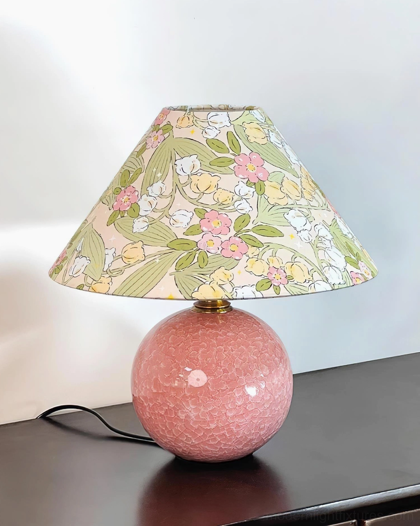 Bloomora table lamp with floral shade and visible power cord on dark wood surface, side angle view