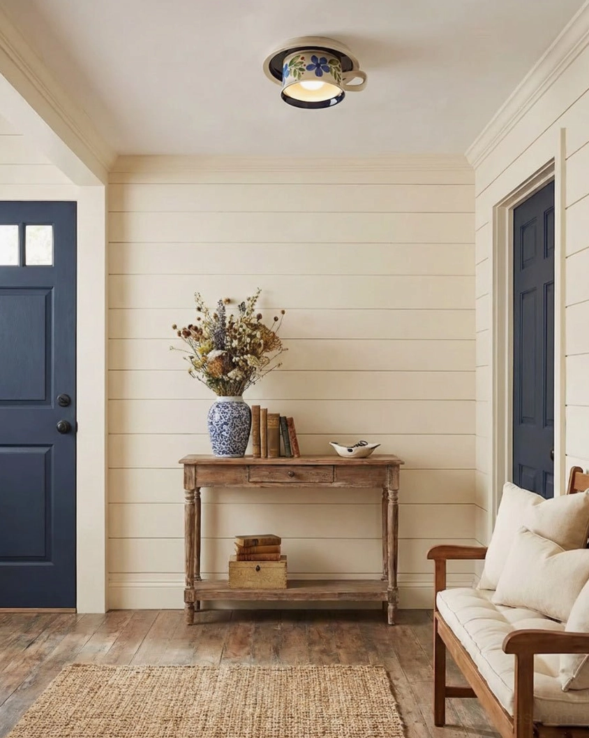 Blue floral tea cup ceiling light in farmhouse entryway with shiplap walls, blue front door, rustic furniture and cottage aesthetic