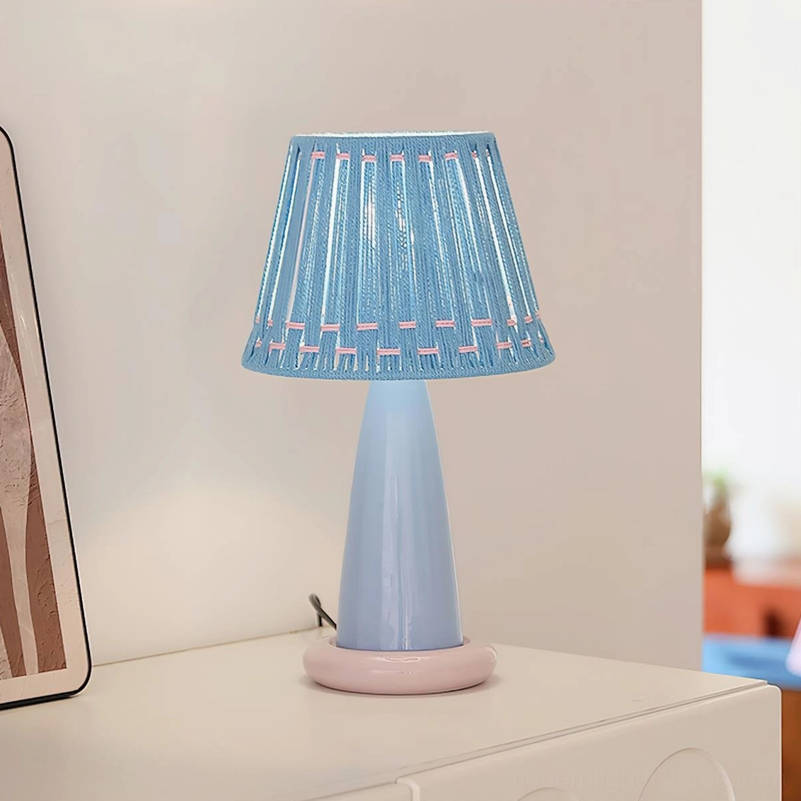 Blue ceramic table lamp with woven shade on white dresser, minimalist modern home decor accessory