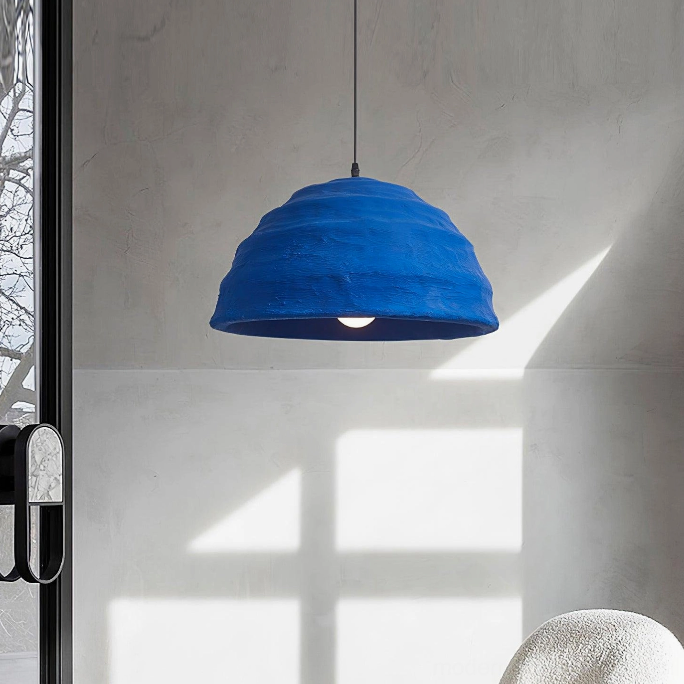 Three-quarter view of azure blue dome pendant lamp in contemporary interior with concrete wall and glass features