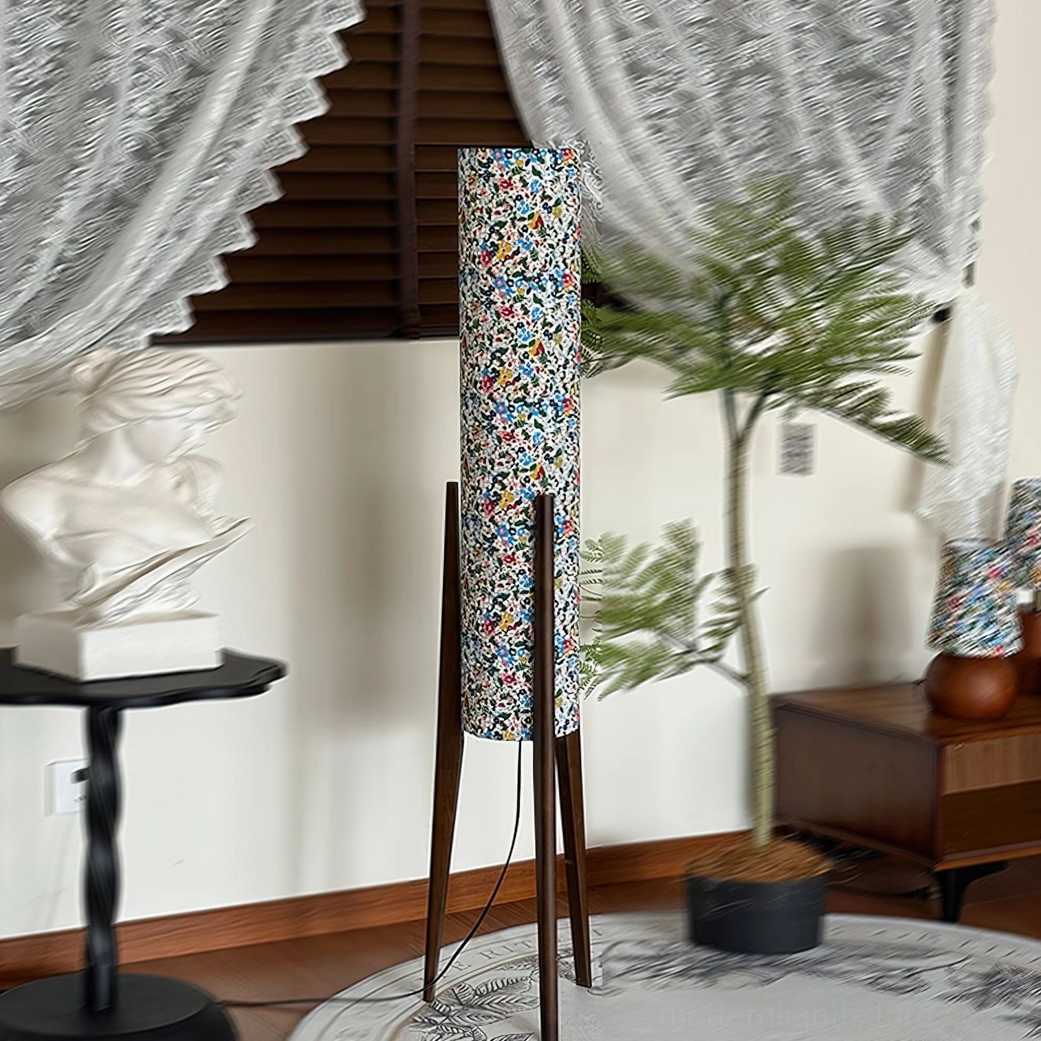 Blue-toned floral print floor lamp with dark brown wooden tripod base in three-quarter side view, vintage interior setting