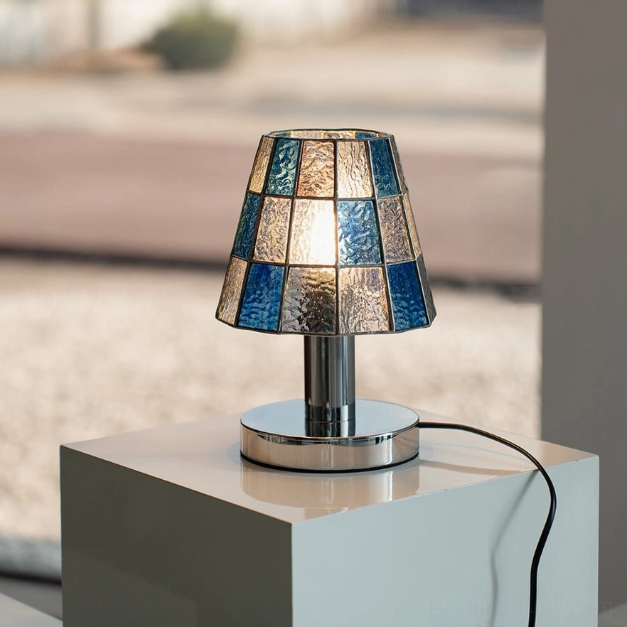 Illuminated blue stained glass geometric table lamp on display plinth with modern minimalist styling
