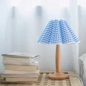 Blue gingham table lamp styled on tabletop with stacked books, warm cottage home decor styling