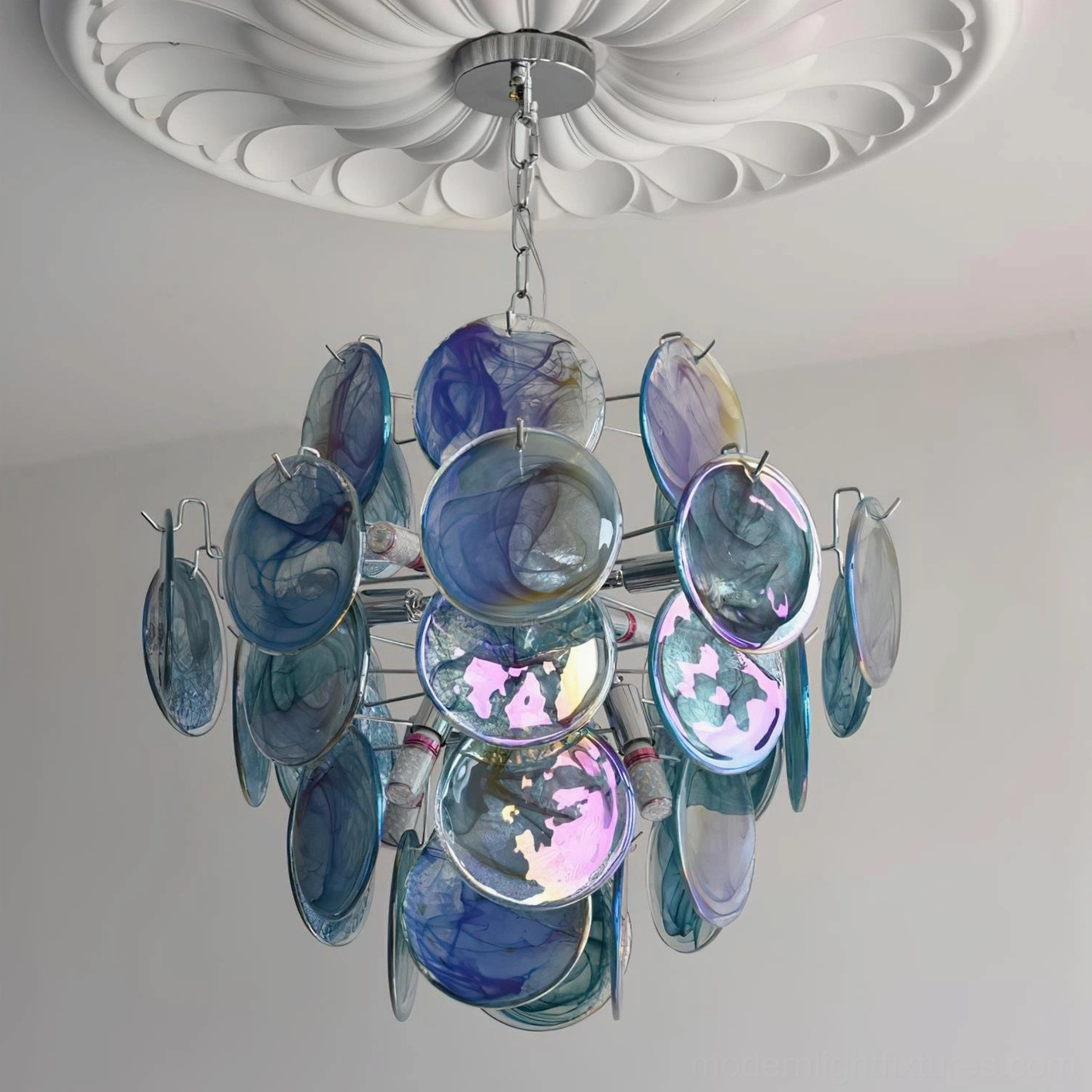 Blue iridescent glass disc chandelier mounted on ceiling with decorative medallion, showing layered glass disc composition