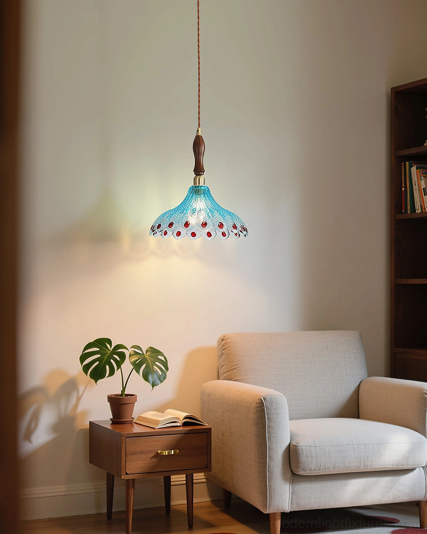 Small decorative blue glass pendant light with red dot accents hanging in cozy living room corner