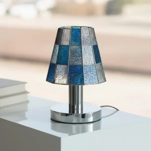 Modern Tiffany-style table lamp with cool blue glass shade displayed on side table with outdoor background