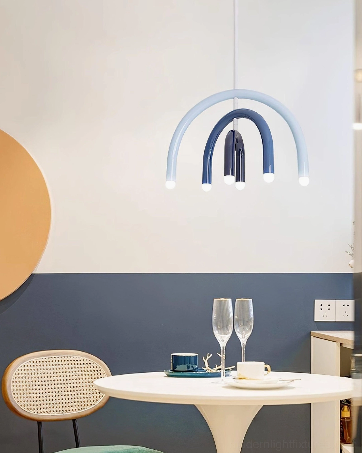 Blue gradient arc pendant light fixture installed in small modern dining nook area