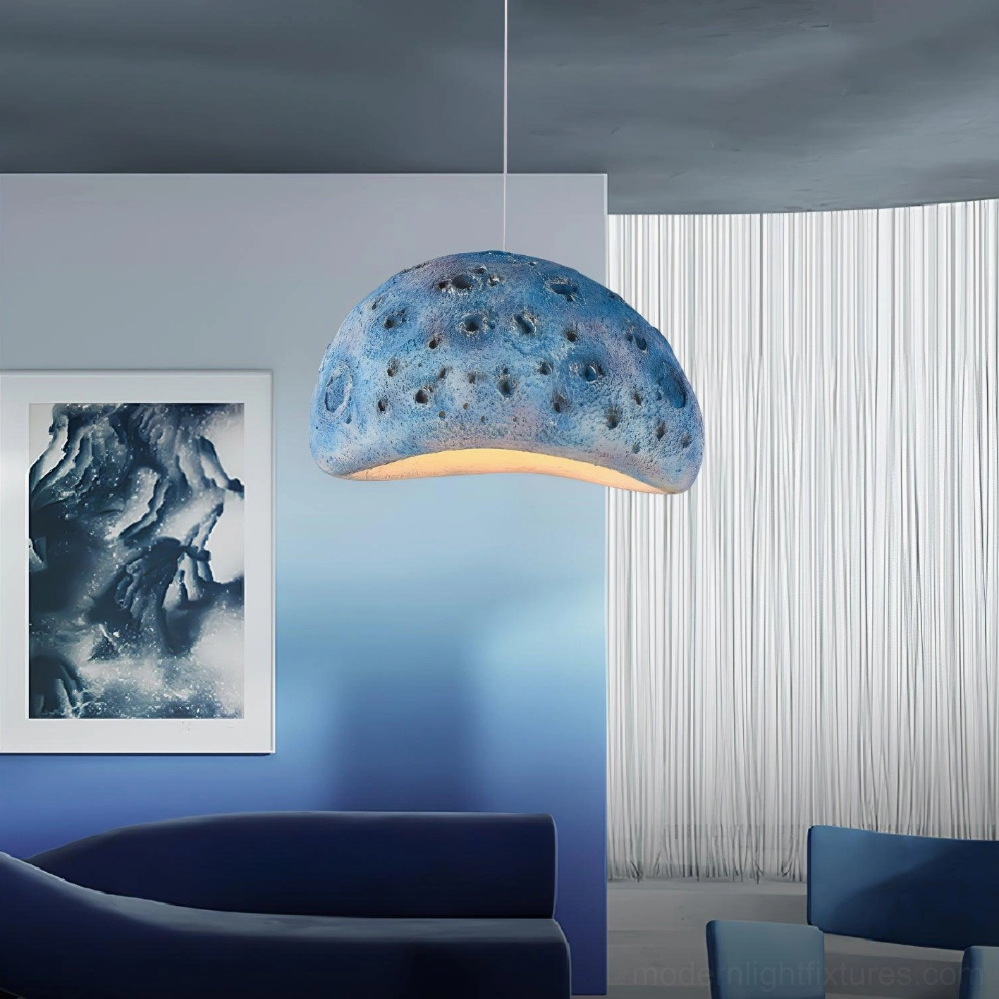 Blue meteorite crater pendant light with textured dome and warm underglow in contemporary leisure space with navy sofa