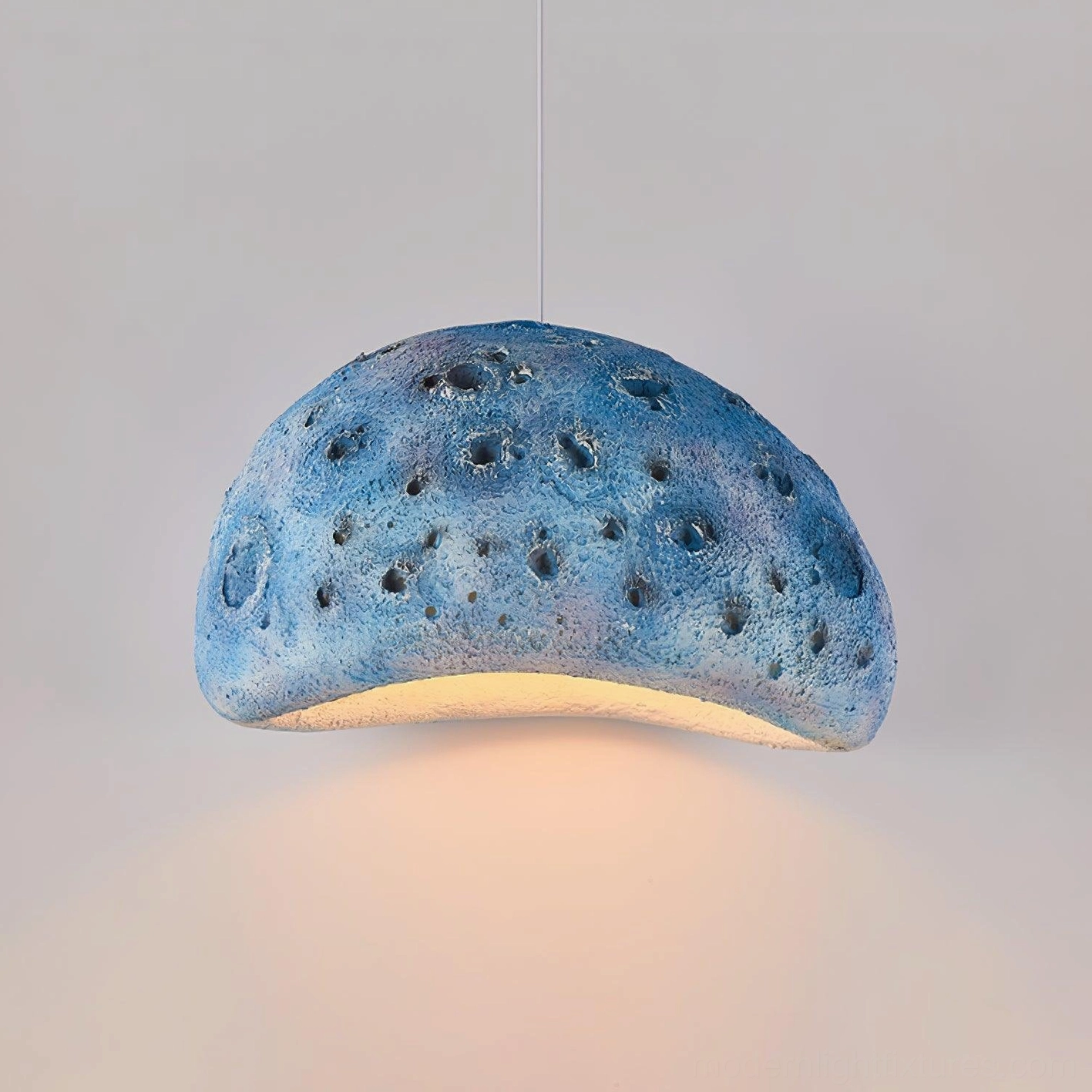 Blue meteorite crater pendant light in contemporary interior with neutral palette and minimalist aesthetic