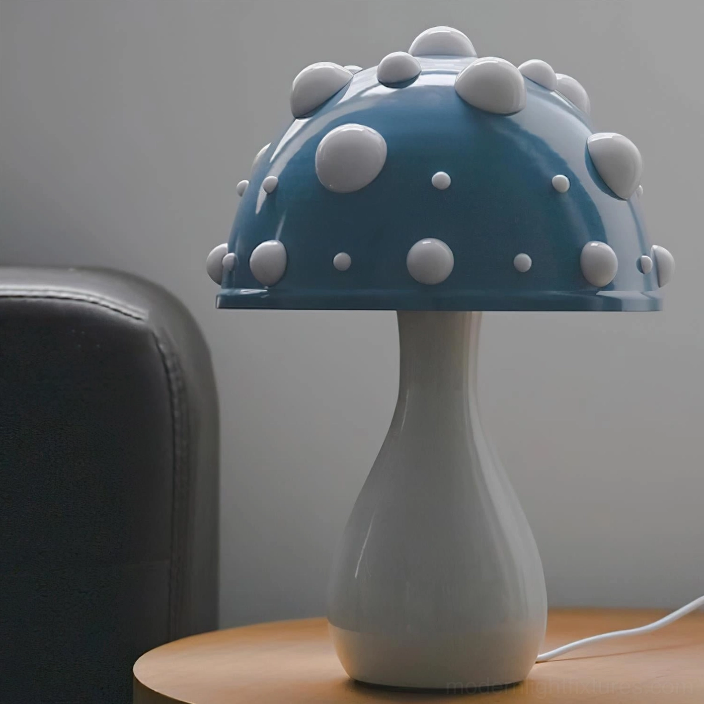 Blue spotted mushroom table lamp with matte blue cap and white rounded accent dots, three-quarter view on home side table