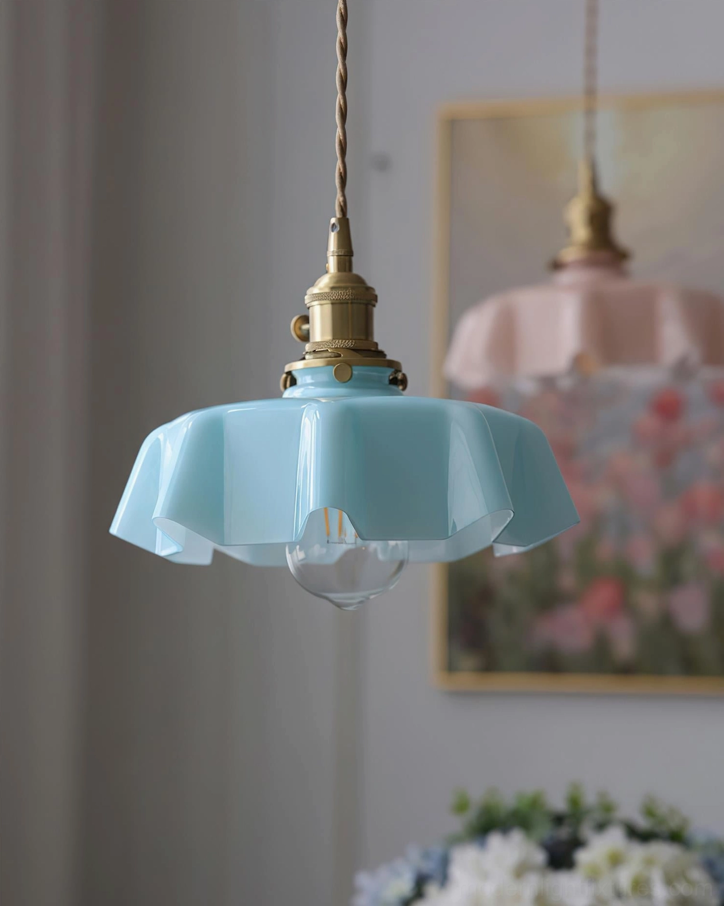 Blue pleated fabric-inspired glass pendant light hanging in home interior with floral artwork and side view
