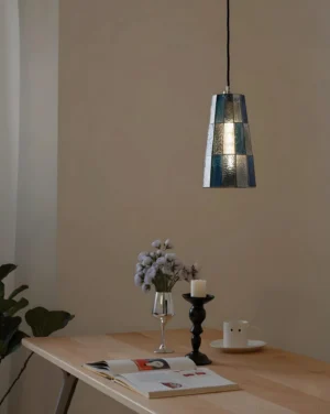 Compact sapphire blue stained glass pendant light illuminated over minimalist dining table interior - warm glowing vintage aesthetic