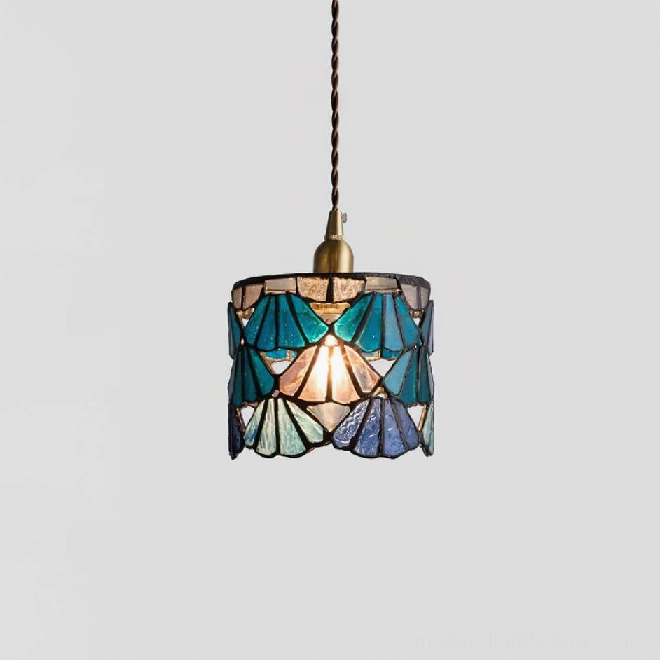 Blue Tina stained glass pendant light casting cool tinted glow over dining table setting