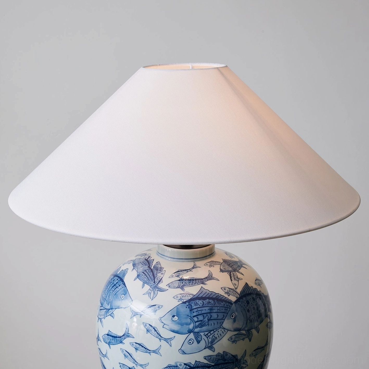 Blue and white ceramic table lamp base close-up, showing hand-painted cobalt fish patterns and white glaze details
