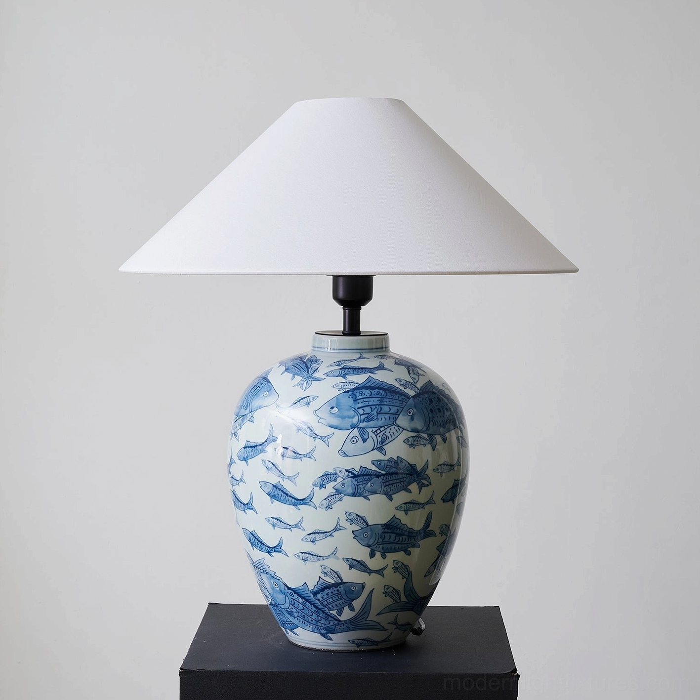 Blue and white ceramic table lamp illuminated, demonstrating warm light diffusion through white fabric shade