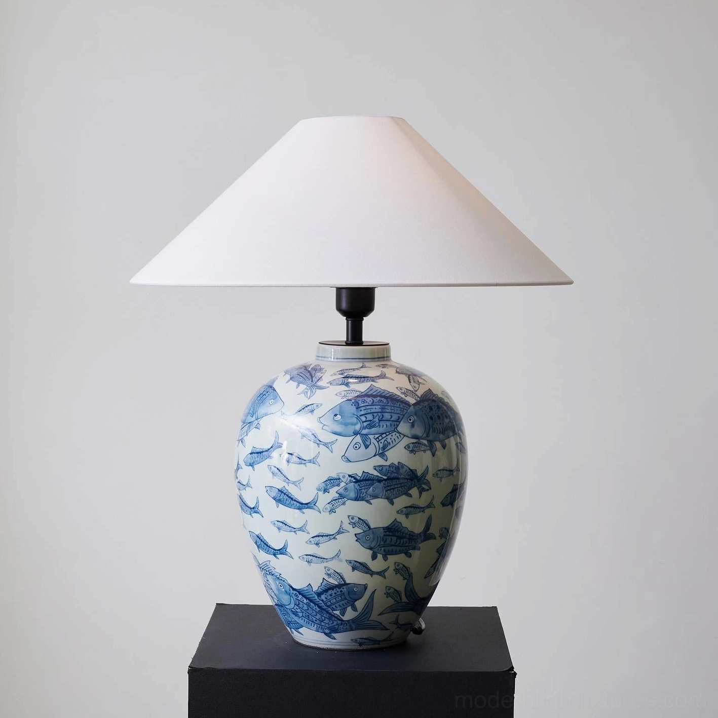 Hand-painted blue and white ceramic table lamp with traditional fish motifs, architectural lighting product photography