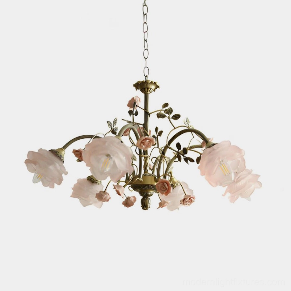 Blush pink floral chandelier with antique brass frame on white background, romantic garden-inspired design with delicate rose and vine detailing