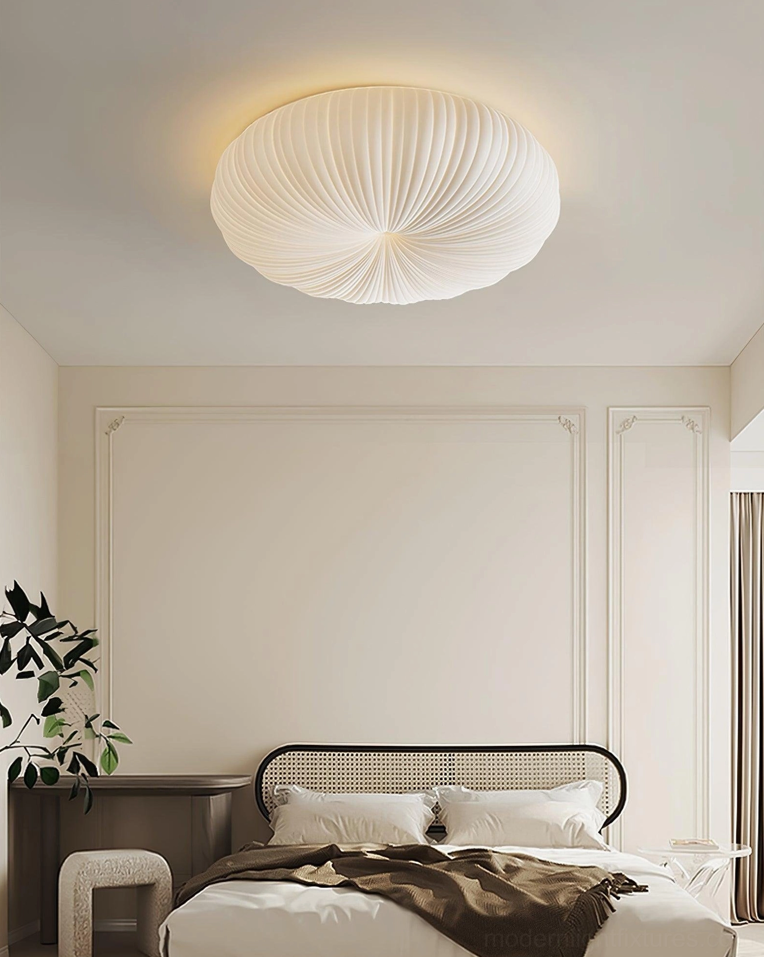 Bobby pleated flush ceiling light in modern bedroom with paneled accent wall, rattan bed frame and potted green plants