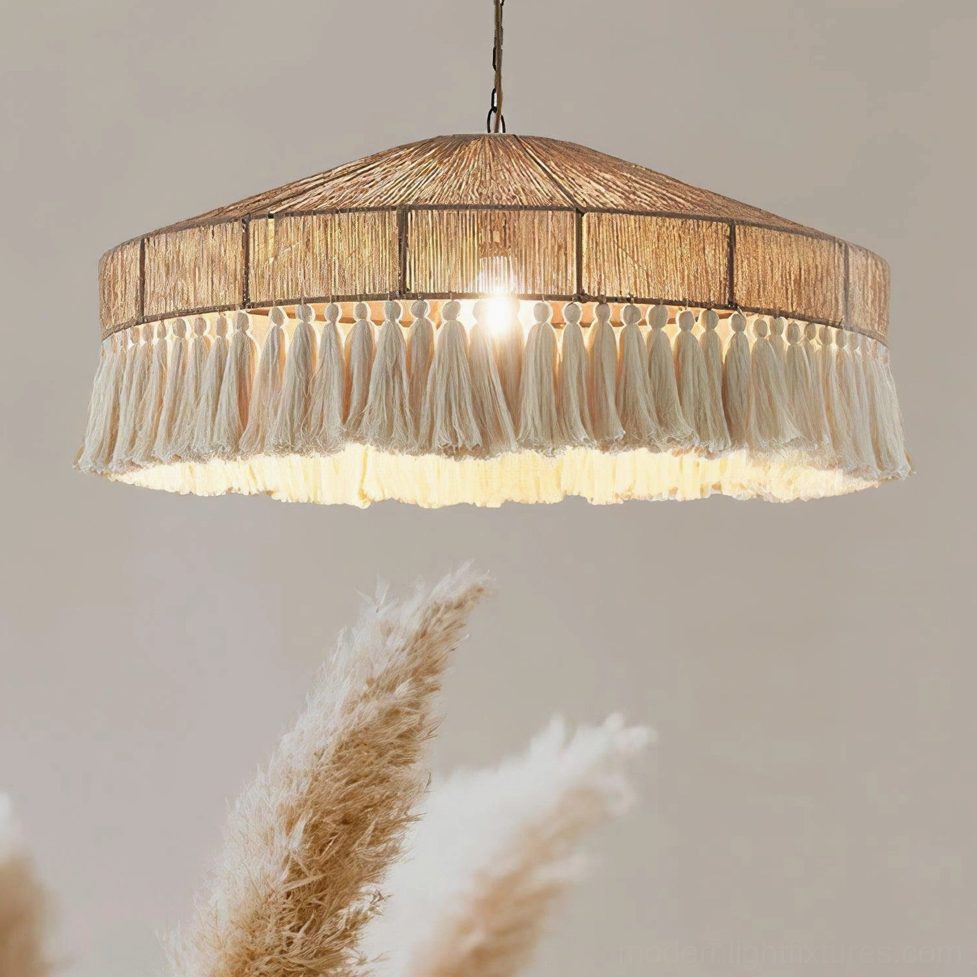 Bohemian tassel pendant light with warm ambient glow, close-up low-angle view highlighting handwoven hemp rope fringe detail and soft light diffusion against dried pampas grass backdrop