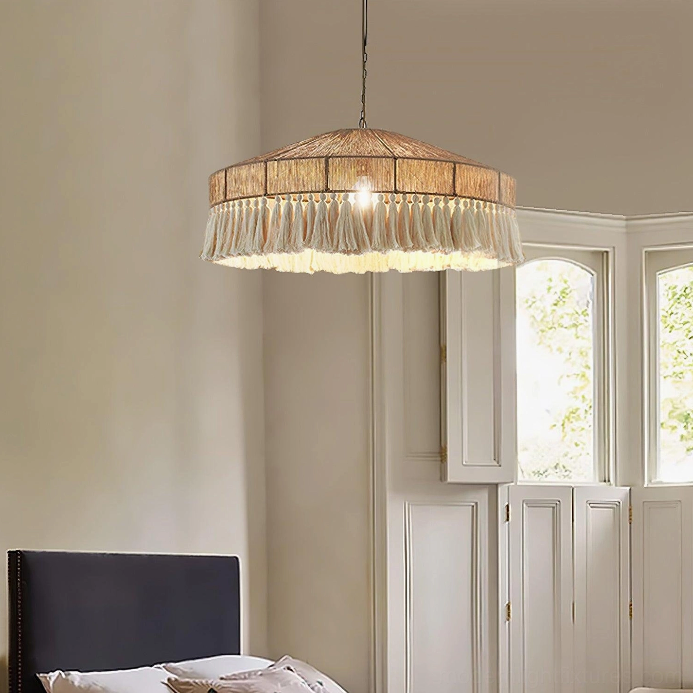 Handwoven bohemian fringe pendant lamp creating warm cozy bedroom ambiance with white french window and natural daylight in boho home decoration
