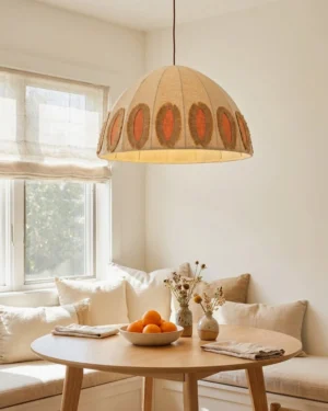 Boho pendant light hanging over round wooden dining table in cozy farmhouse dining room setting