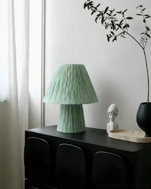 Green striped boho table lamp in modern home interior, placed on minimalist side table with houseplants and decorative objects