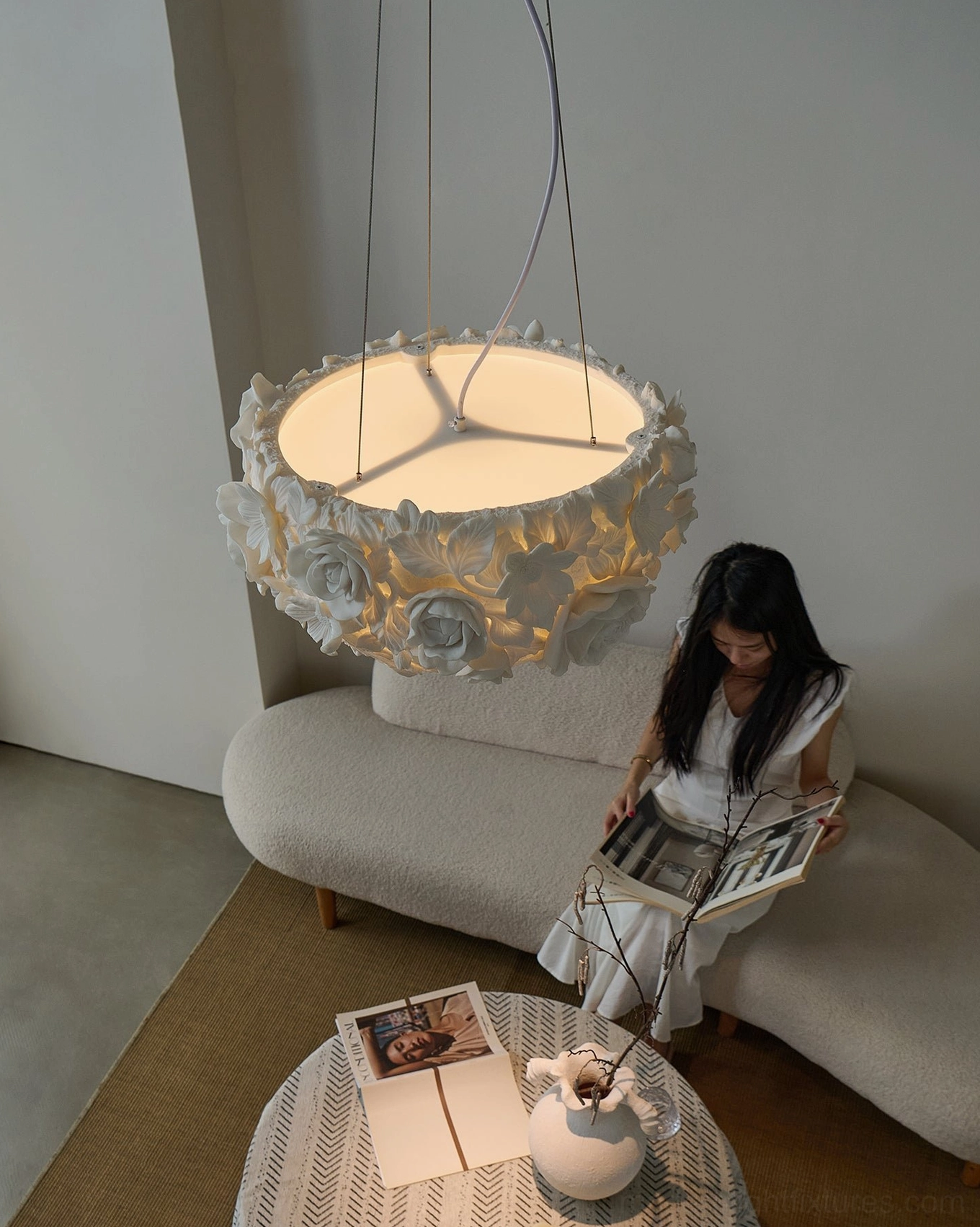 Handcrafted botanical pendant light with detailed ceramic flowers, warm illumination showing light play through petals